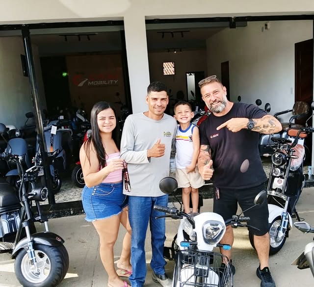 Clientes recebendo scooter elétrica no salão da Caju Mobility